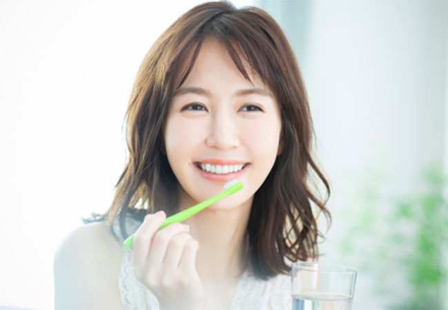 笑顔で歯を磨く女性