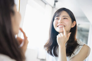 鏡で歯をチェックする笑顔の女性